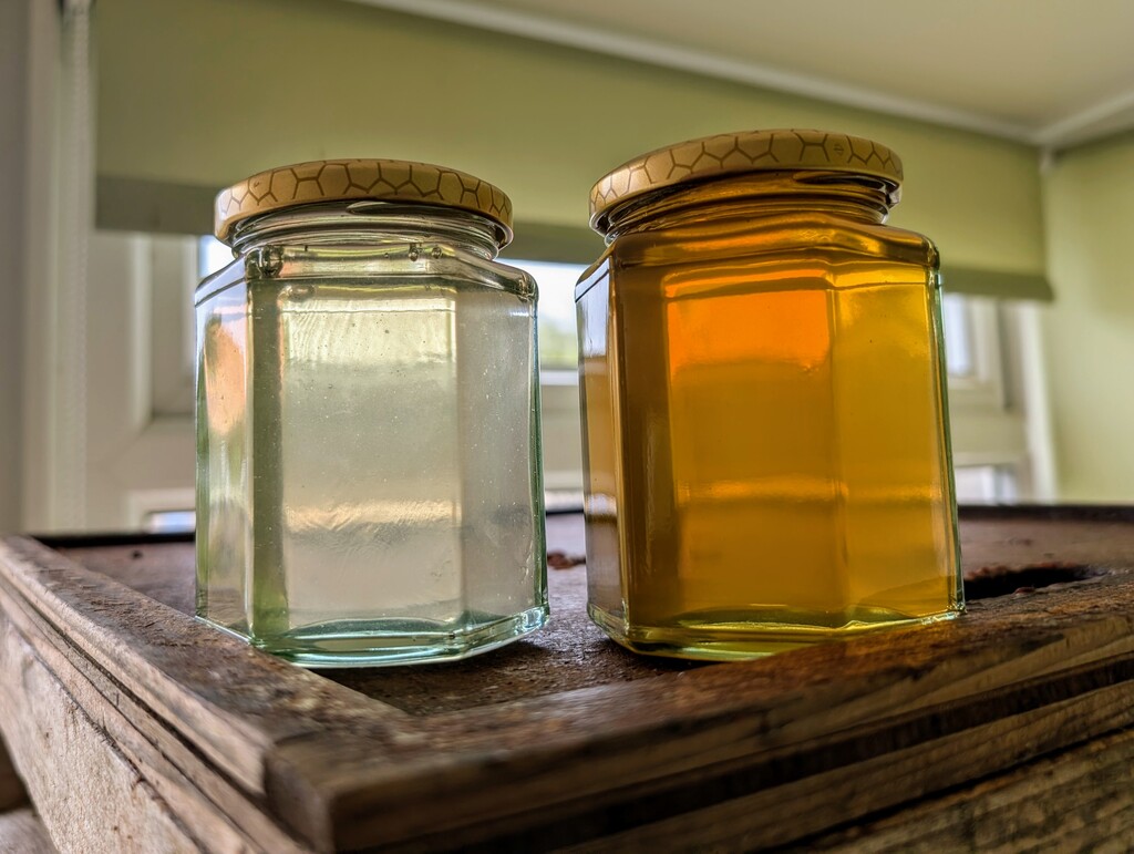 two jars of honey, one almost clear ther other more caramel
